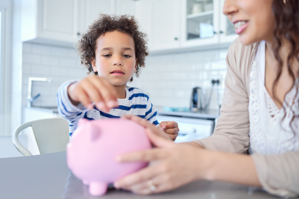 A child inserts coins into a piggybank.